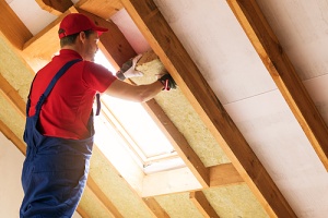 Contractor installing insulation in a residential attic.