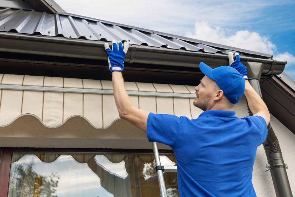 Technician installing rain gutter system on a home.