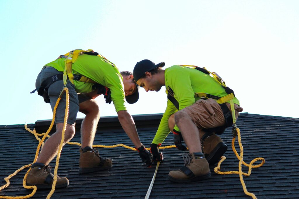 Two male roofers inspecting a roof.