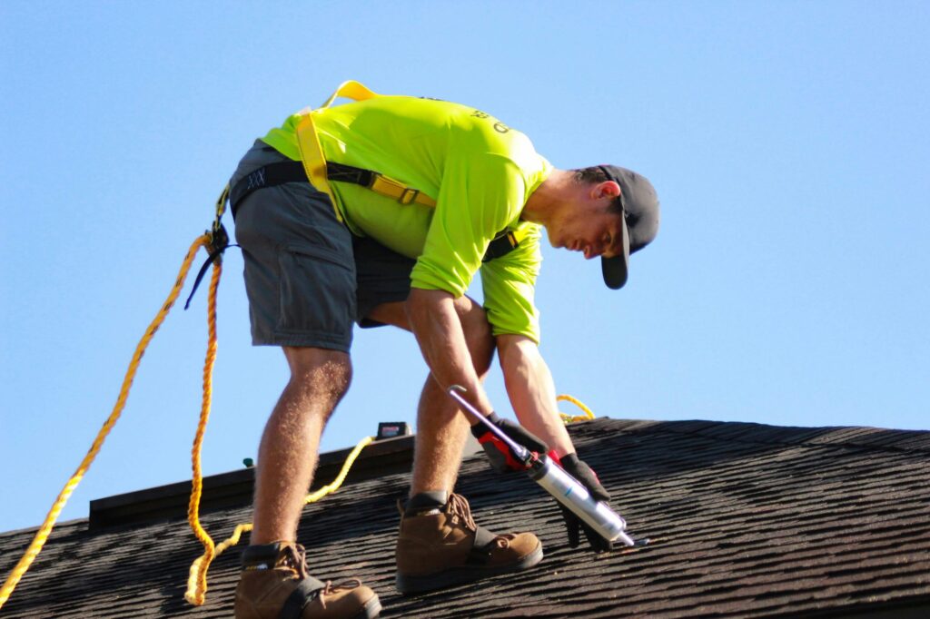 Male roofer caulking a roof.